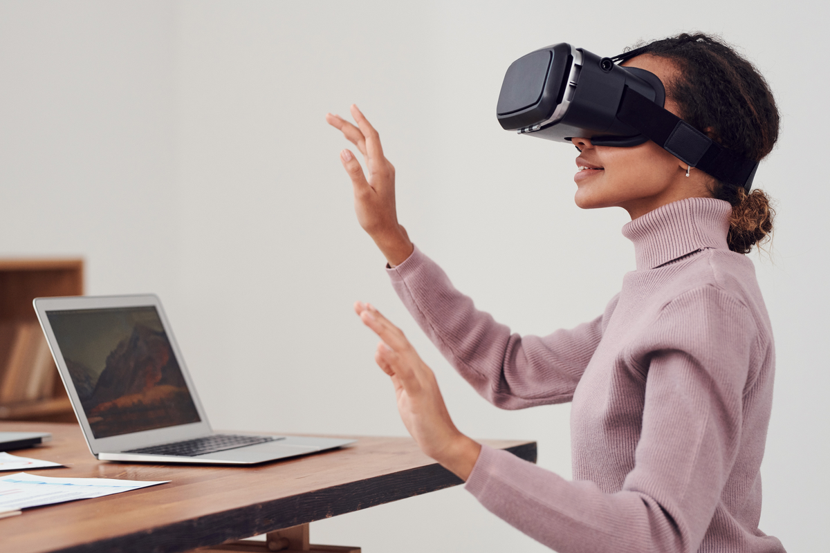 Mulher utilizando um óculos de realidade virtual na frente do computador
